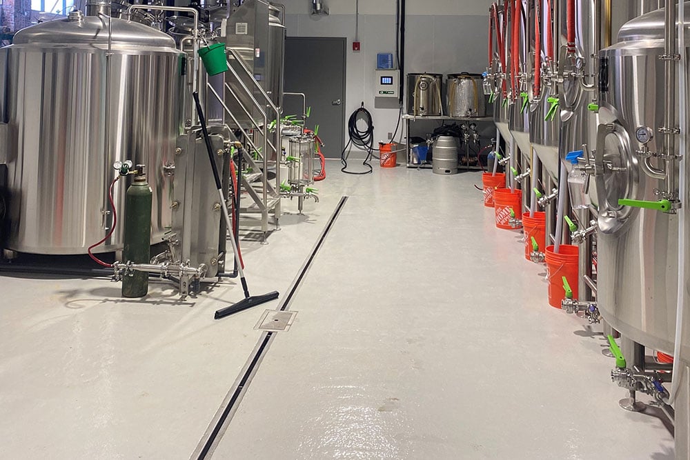 Slot drain and brewery tanks, clean floor with cleaning supplies like hoses, squeegees and buckets 