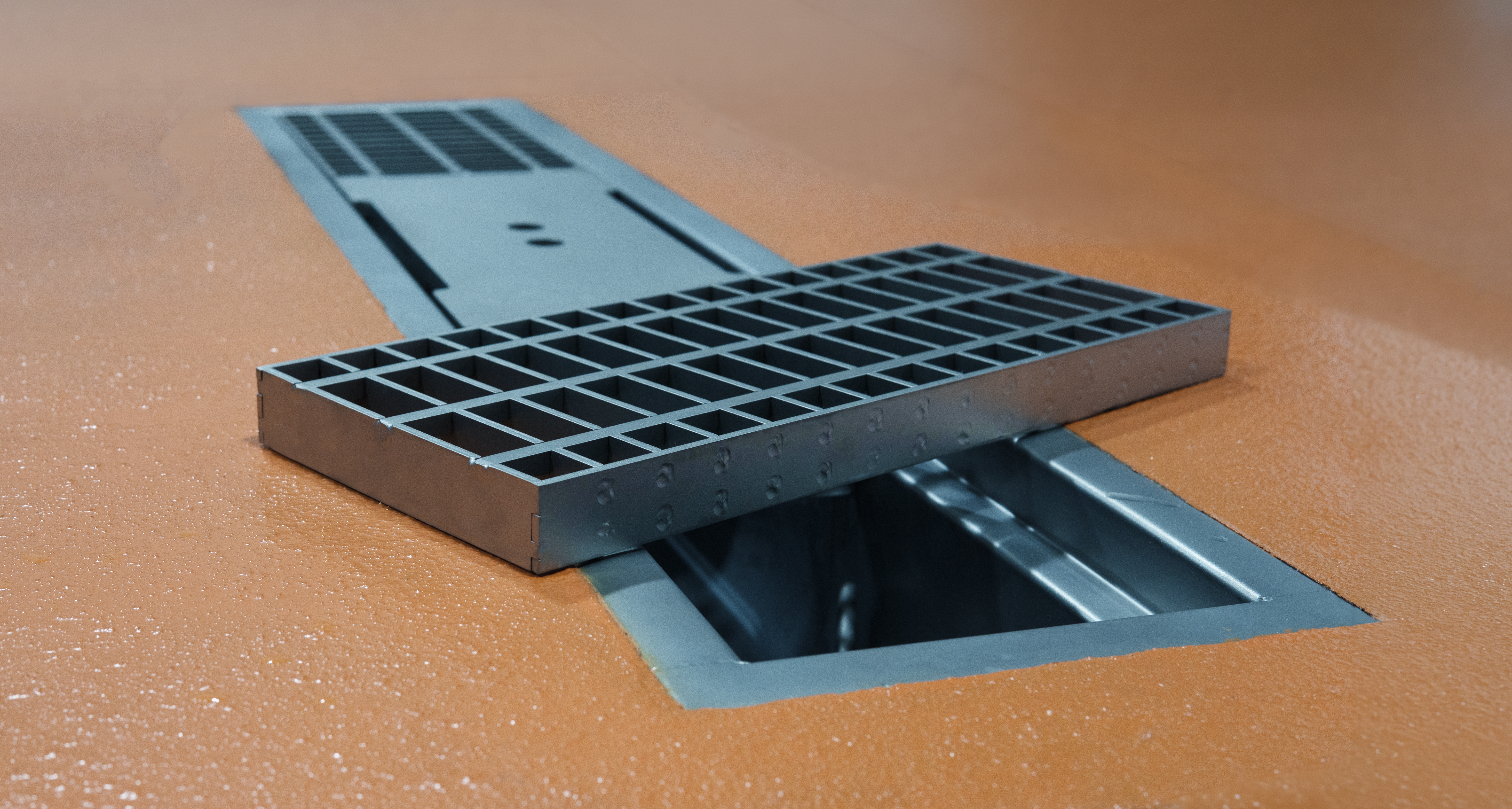Hygienic stainless steel trench drain with closeup of grate sitting across drain.